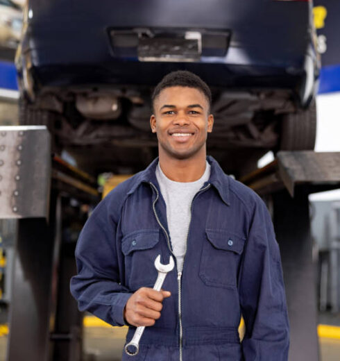 Portrait of a happy African American mechanic working at an auto repair shop and looking at the camera smiling